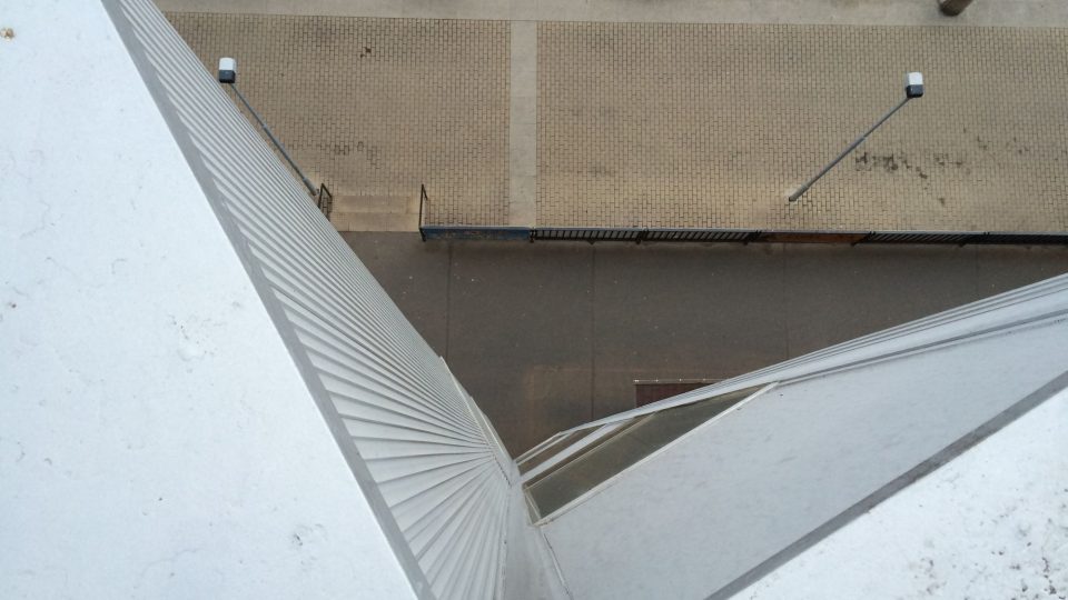 Kolmý pohled ze střechy přes členitou fasádu na ulici