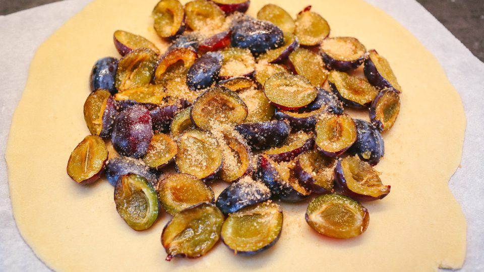 Vypekockované a přepůlené švestky nahrneme doprostřed koláče a rozprostřeme | foto: Jana Volková Vypekockované a přepůlené švestky nahrneme doprostřed koláče a rozprostřeme