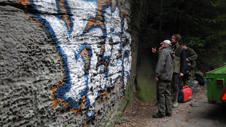 Neznámý vandal posprejoval pískovcovou skálu stříbrnou, modrou a červenou barvou