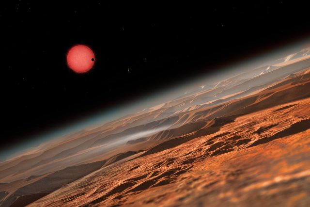 Chladná trpasličí hvězda TRAPPIST-1 při pohledu z oběžné dráhy kolem jedné z jejich planet,  v představě výtvarníka | foto:  ESO/M. Kornmesser,  CC BY 4.0