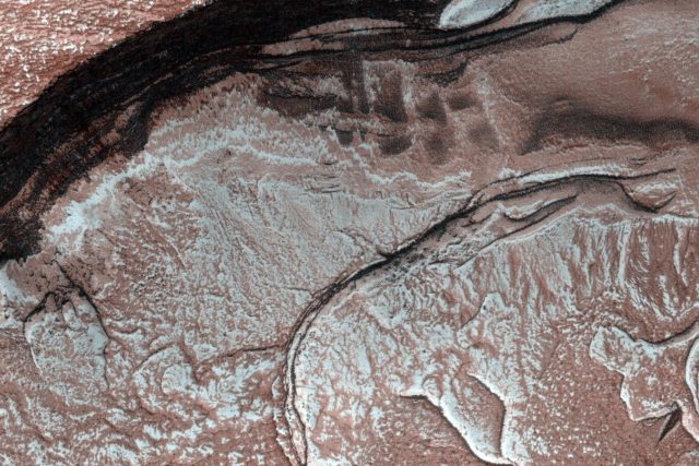 První sluneční světlo na konci zimy zvolna proniká do oblasti severní polární čepičky Marsu. Dno kaňonu Chasma boreale je skryto ve stínu. Povrch pokrývá zmrzlý oxid uhličitý smíšený s prachem | foto: Public domain,   NASA/JPL-Caltech/University of Arizona